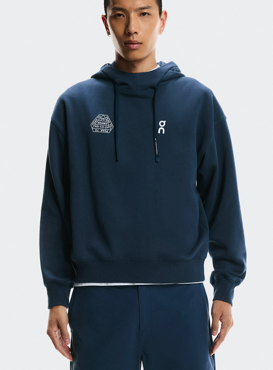 Model a wearing navy blue hoodie with On Running and BEAMS x REI CO-OP logo.