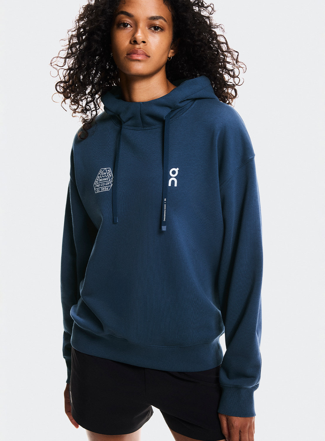 Model a wearing navy blue hoodie with On Running and BEAMS x REI CO-OP logo.
