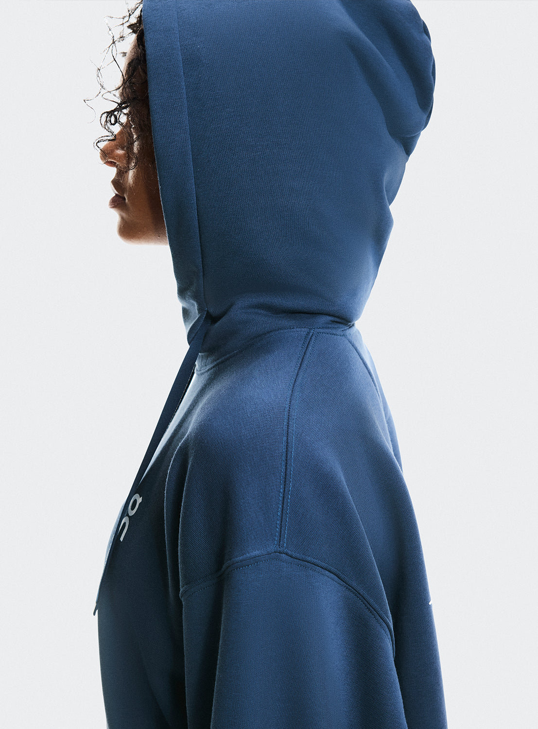 Side view of a model wearing a navy blue hoodie showcasing the hoodie detail. 