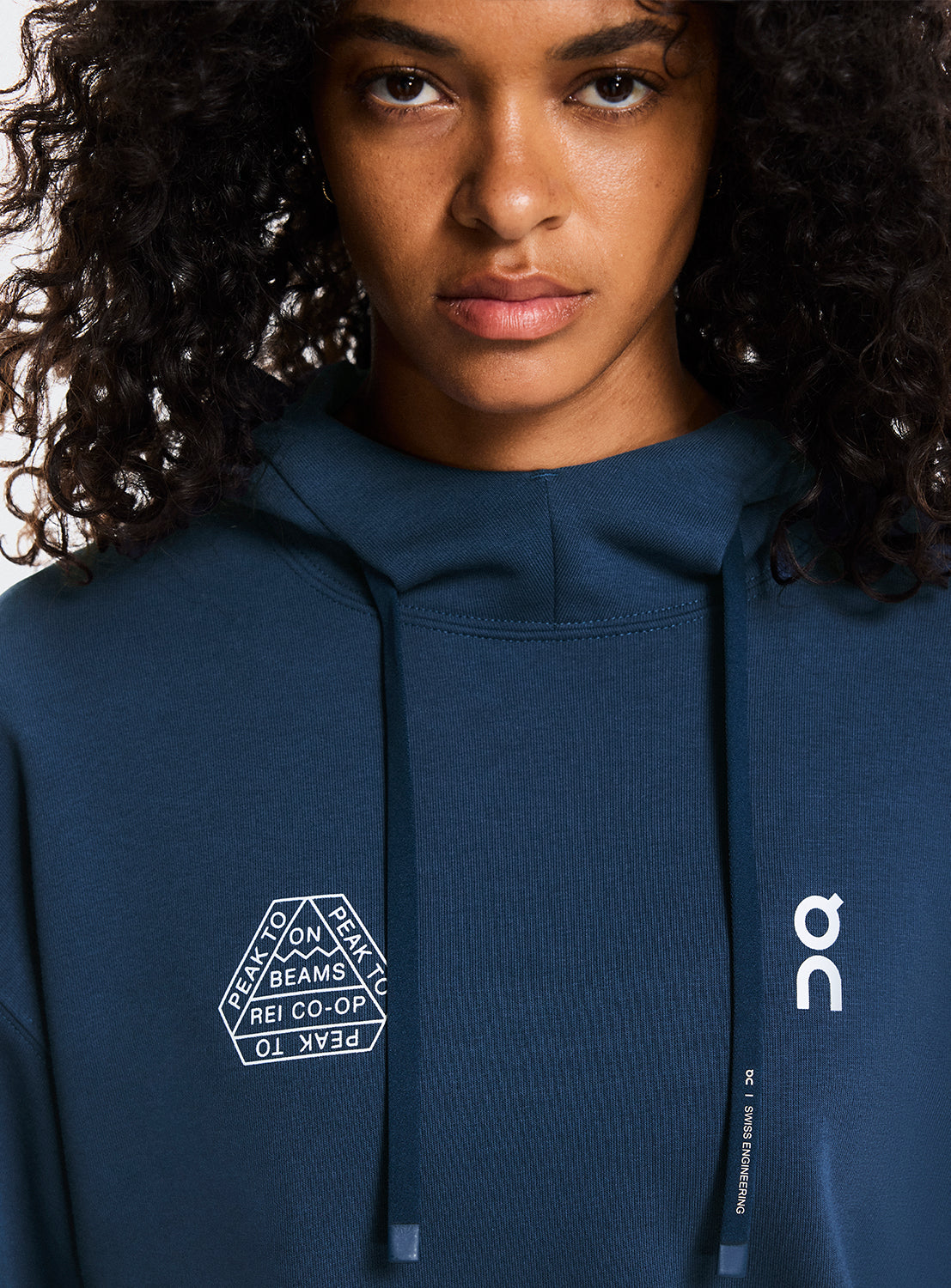 Model a wearing navy blue hoodie with On Running and BEAMS x REI CO-OP logo.