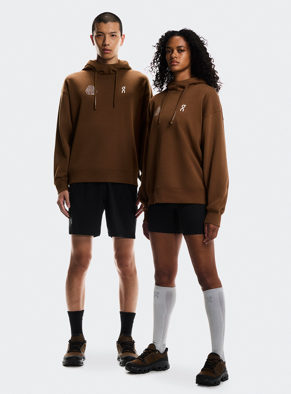Model wearing brown hoodies with On Running and BEAMS x REI CO-OP logo.