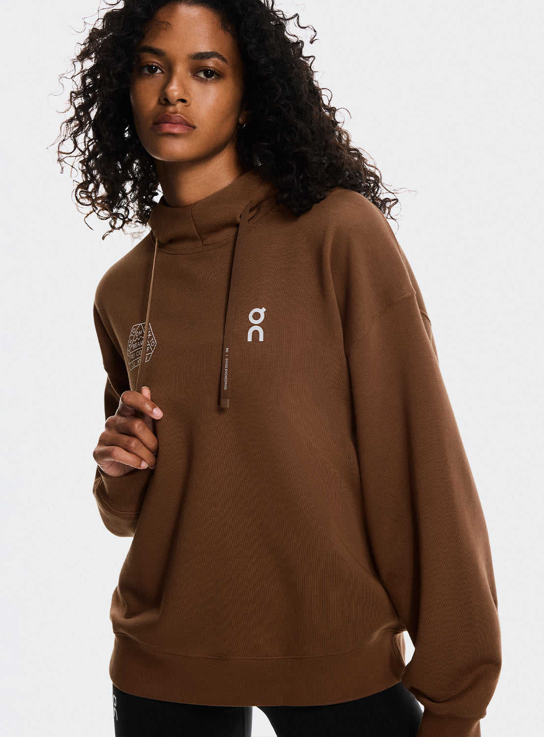 Models a wearing brown hoodie with On Running and BEAMS x REI CO-OP logo.