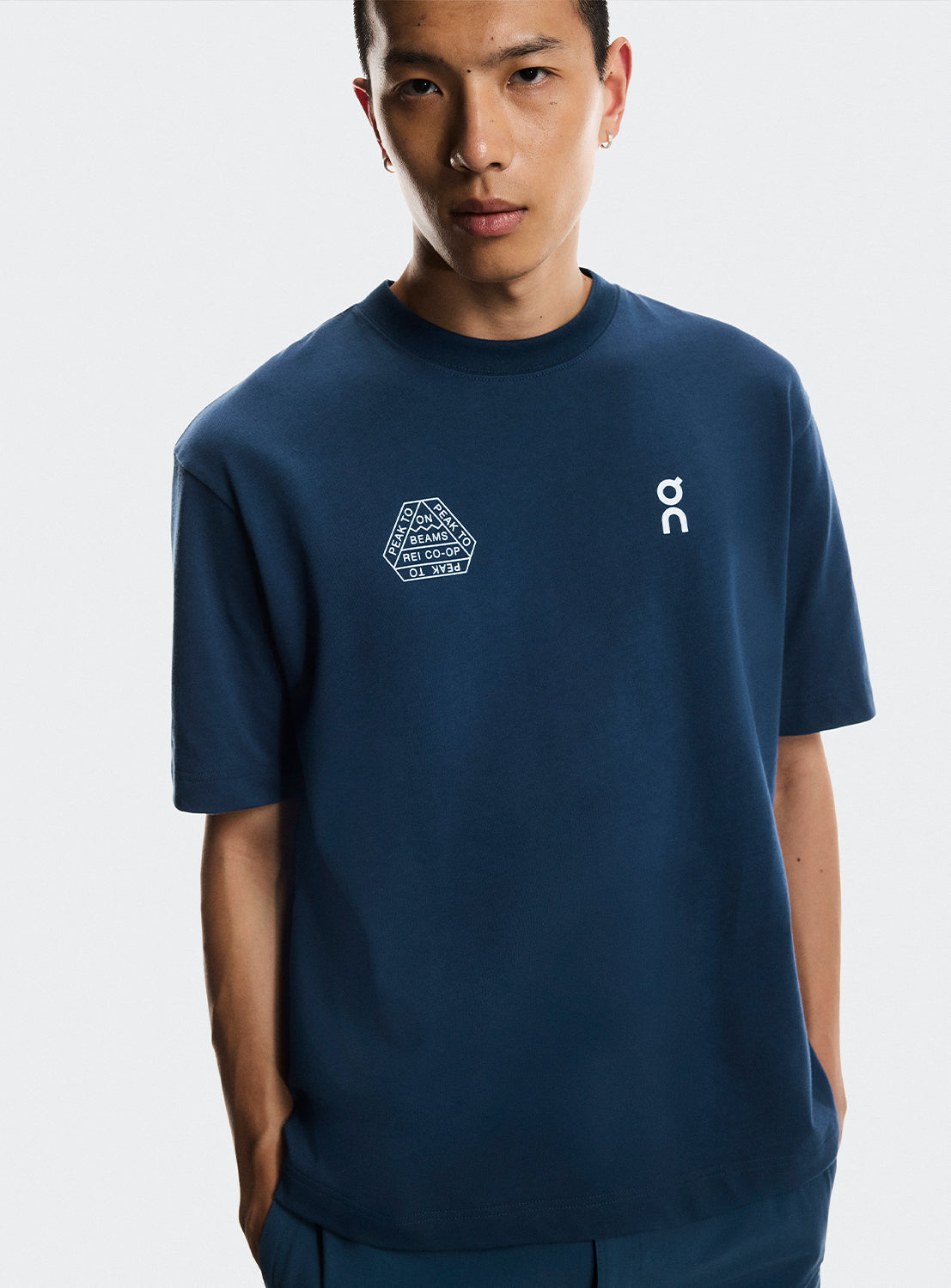 Model wearing navy blue t-shirt ON Running, BEAMS, and REI CO-OP logos. 
