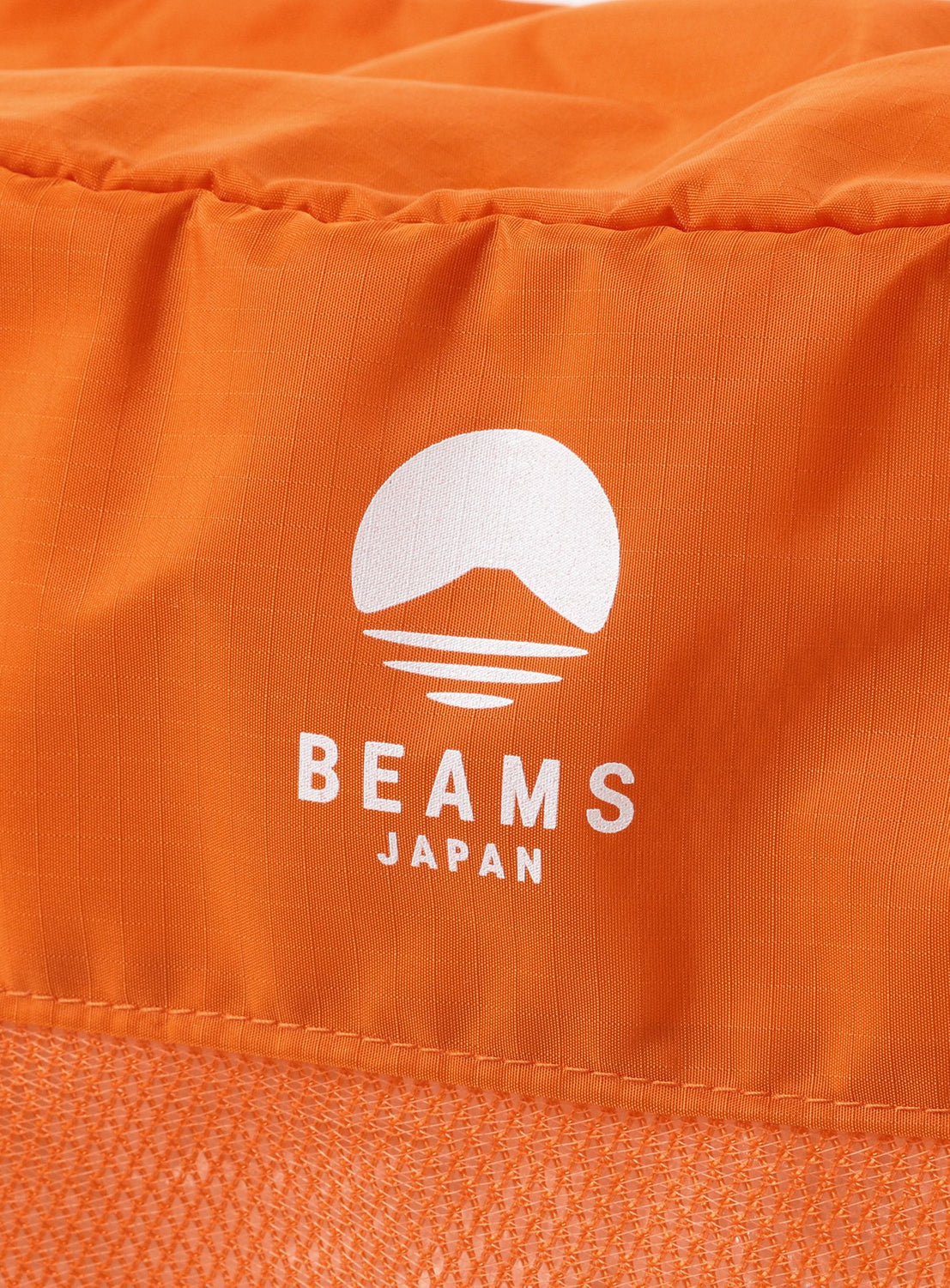 Close-up of an orange fabric surface with a white 'Beams Japan' logo.