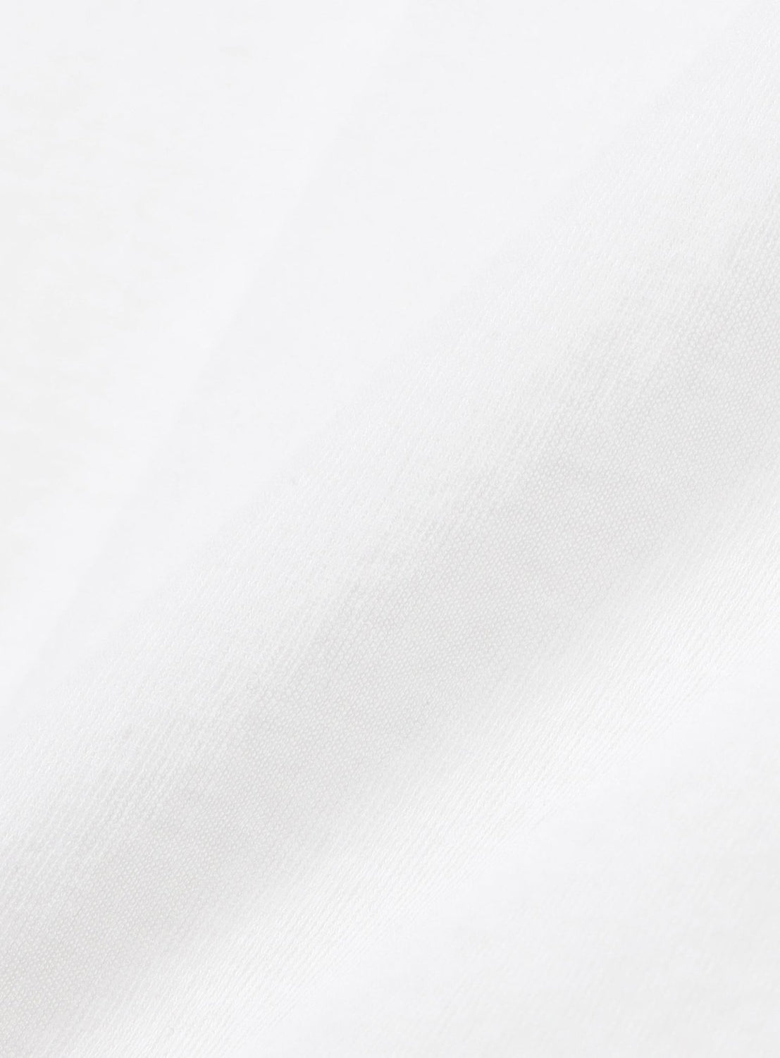 A close-up of smooth white fabric with gentle folds and shadows, highlighting the texture—ideal for Ernie Palo's Sheer Henley Neck T-Shirt, a lightweight half-sleeve top that offers modern feminine style.