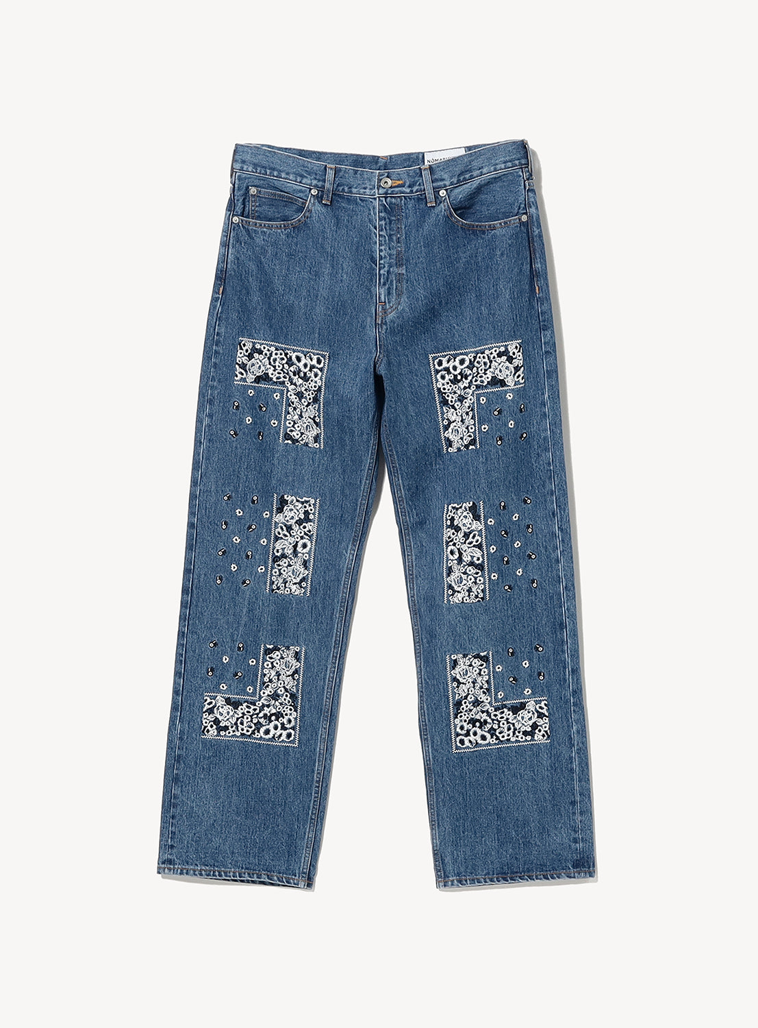Bandana Embroidery Denim Pants by NOMARHYTHM TEXTILE are crafted from premium Okayama denim in Japan. These straight-leg blue jeans feature distinctive hand-embroidered black and white patterned fabric patches and silver stud accents, arranged in square and rectangular designs on the front of both legs.