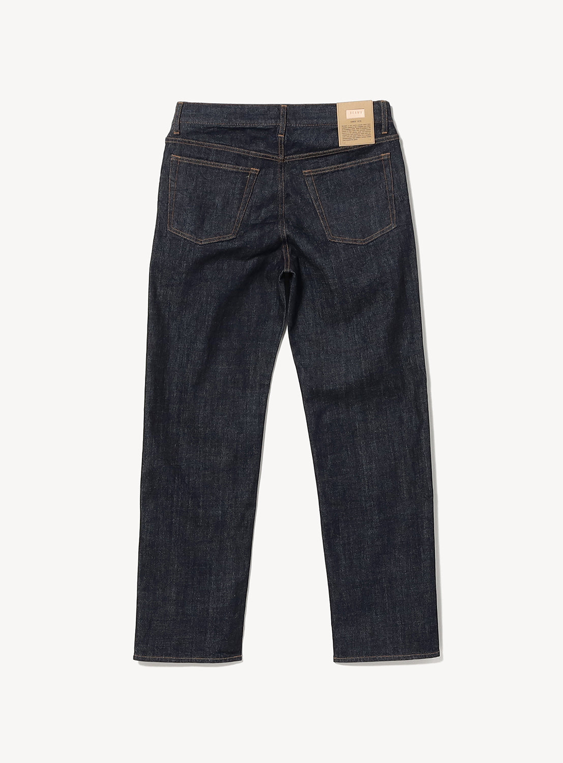 Back view of BEAMS Comfy 5-Pocket Denim in slim fit dark indigo Japanese denim, featuring two back pockets and a tan leather patch on the waistband.