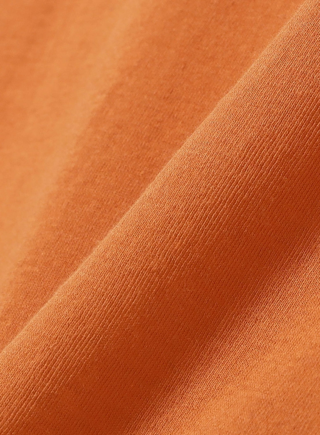 Close-up of orange, lightweight Sheer Henley Neck T-Shirt by Ernie Palo, highlighting its soft texture and fine knit pattern with gentle folds and shadows for a feminine styling effect.