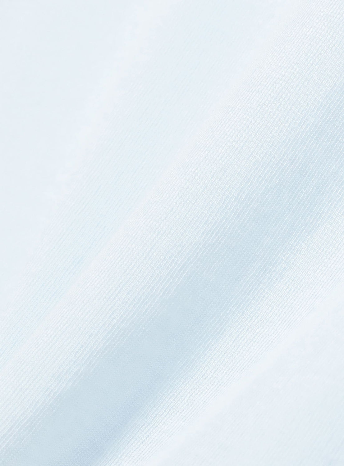 Close-up of smooth, light blue fabric with a subtle diagonal texture and soft folds, ideal for the Ernie Palo Sheer Henley Neck T-Shirt—a lightweight piece that enhances gentle light and shadow for feminine styling.