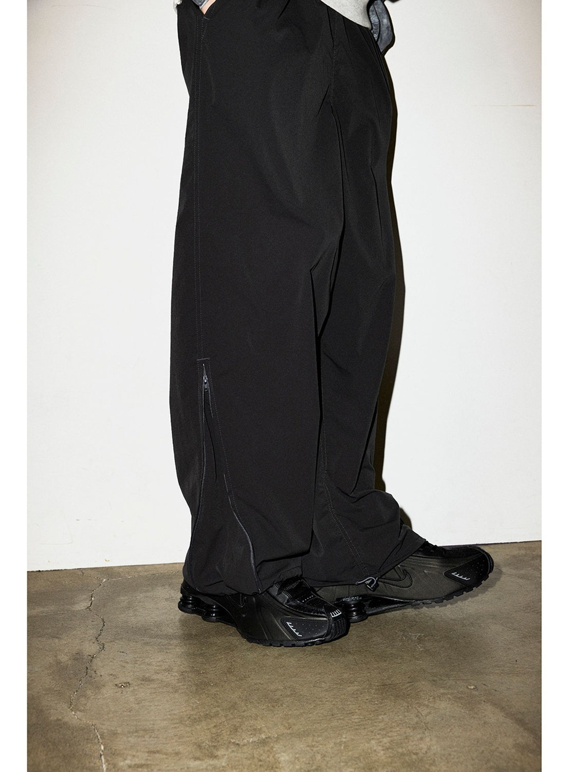 Black BEAMS Technical 2-Way Adjustable Easy Pants with side-leg zippers, worn with black athletic sneakers.