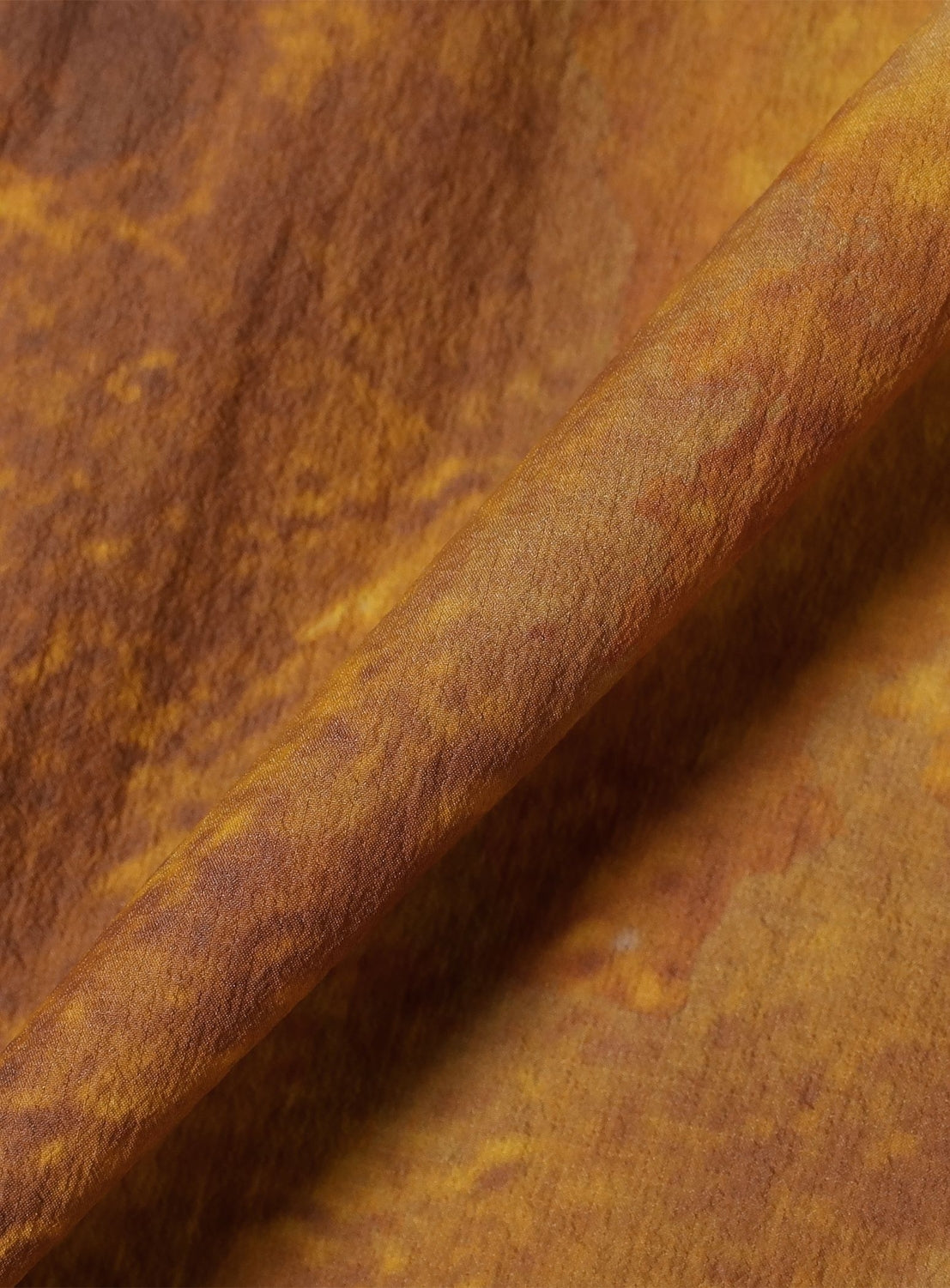 Close-up of a Print Zip Hooded Jacket featuring brown and tan mottled planet print fabric with a folded crease running diagonally across the frame.