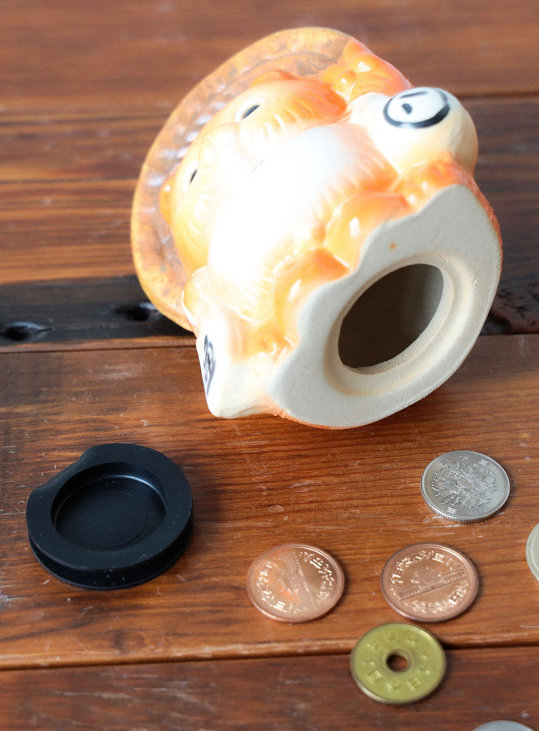 Decorative fish-shaped piggy bank with coins on a wooden surface