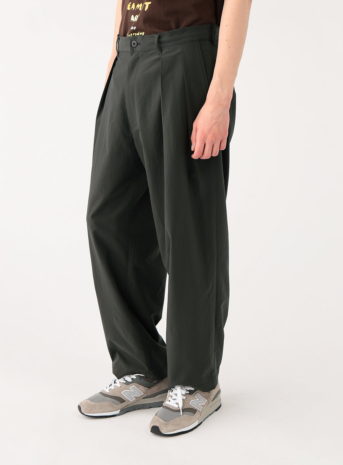 Close-up of a model wearing the charcoal pants, focusing on the leg length and styling with sneakers.