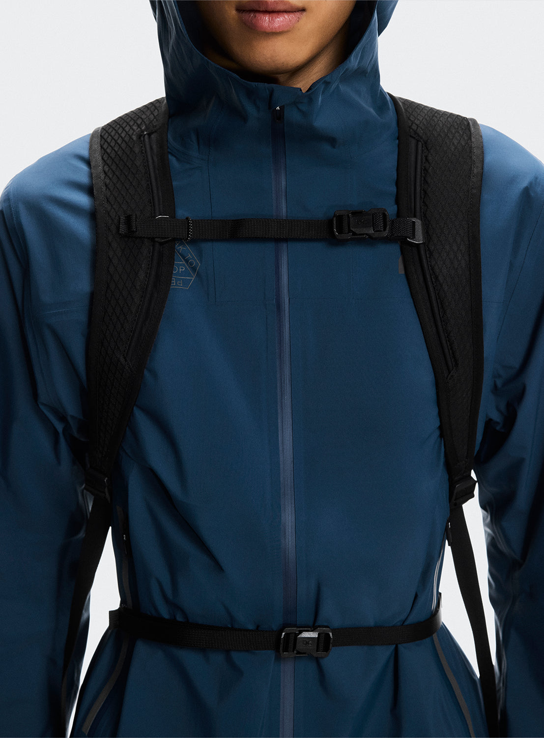 Model wearing the black backpack highlighting the front double clasp and the strap details. 