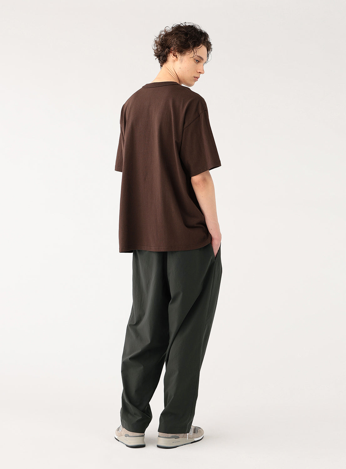 Side view of a model in the charcoal pants, highlighting the full cut and relaxed fit.