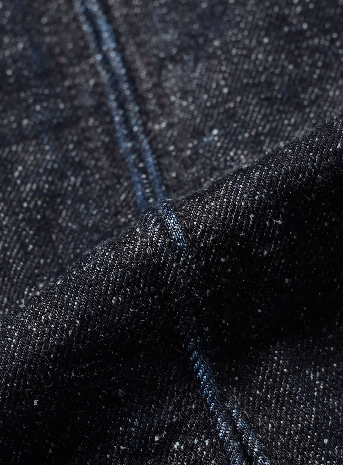 Close-up of textured dark blue nep denim from the BEAMS Nep Denim Zip Jacket, featuring a visible vertical seam.