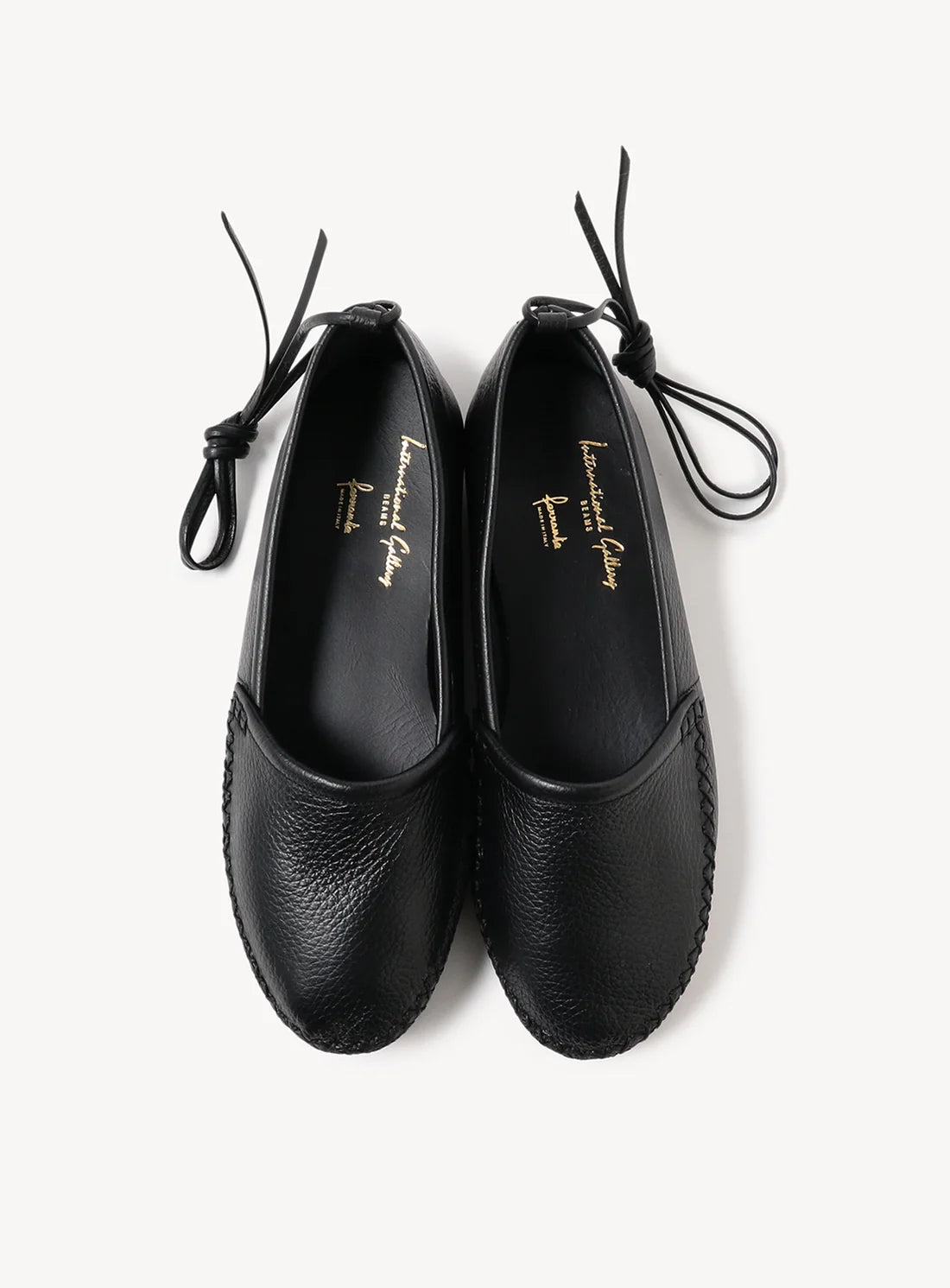 A pair of black leather lace-up flats with tied ankle straps.