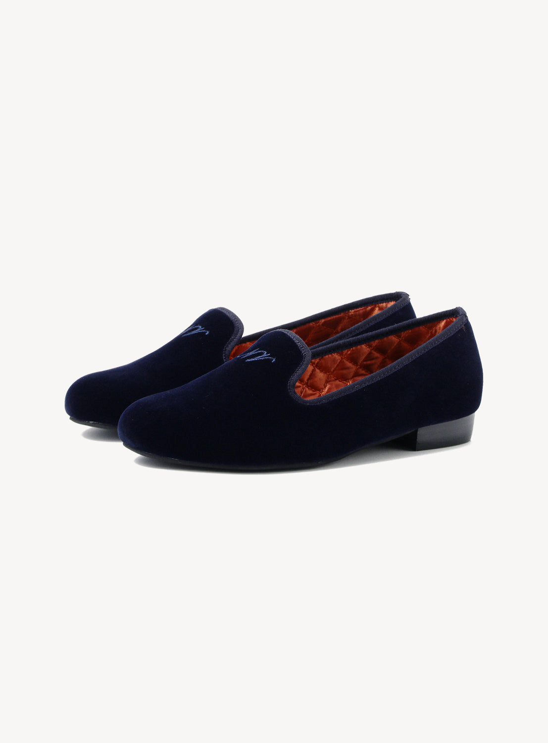 Pair of navy velvet shoes with an orange interior on a white background.