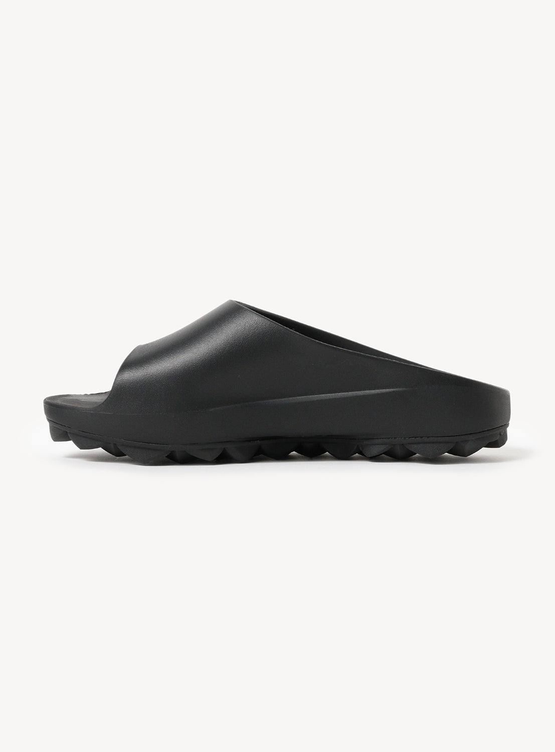 Side view of a single black sandal, showing the silhouette and material.