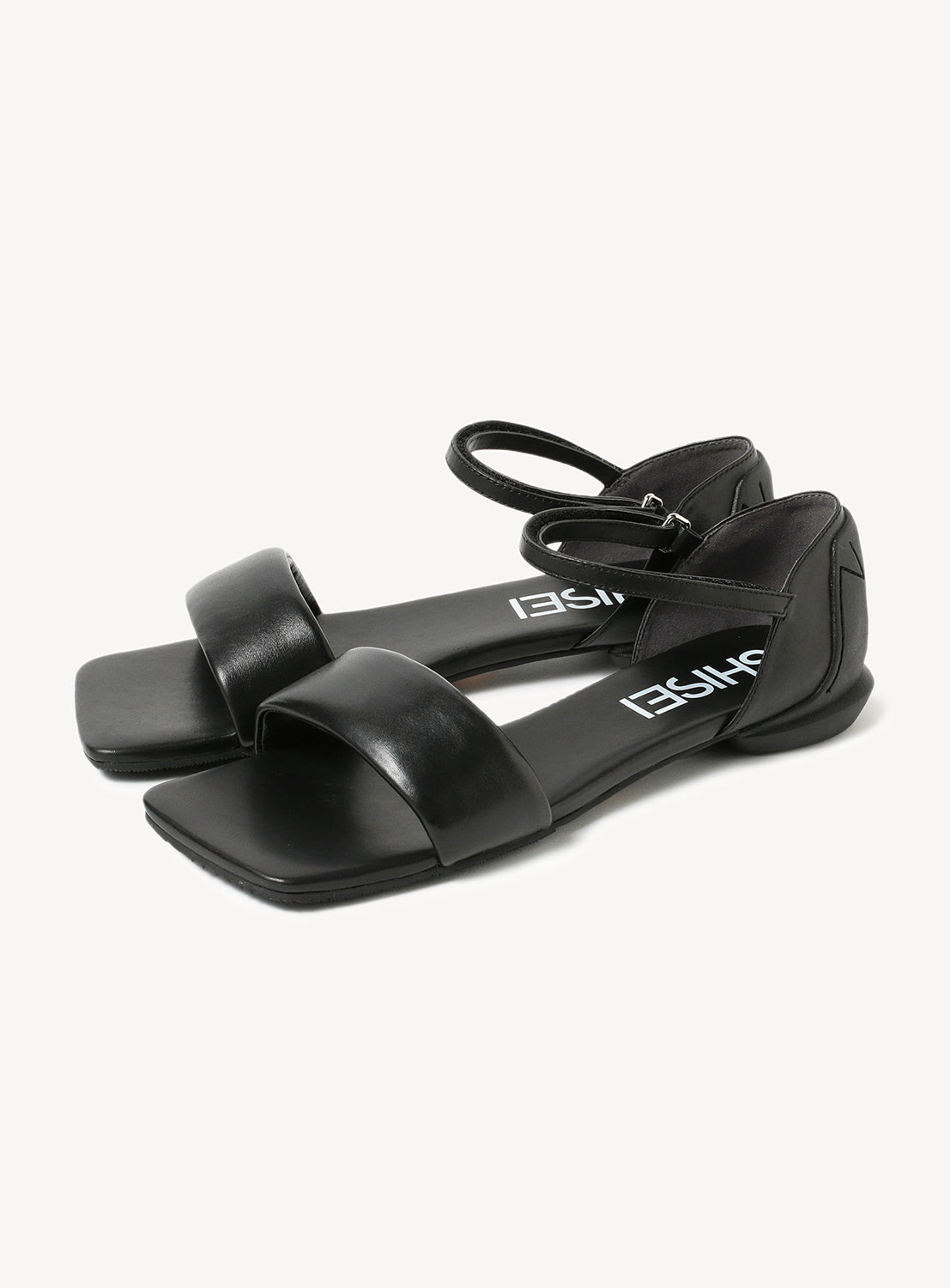 Black flat sandals with a wide toe strap and an ankle strap, showing the "SHISEI" brand name on the insole.