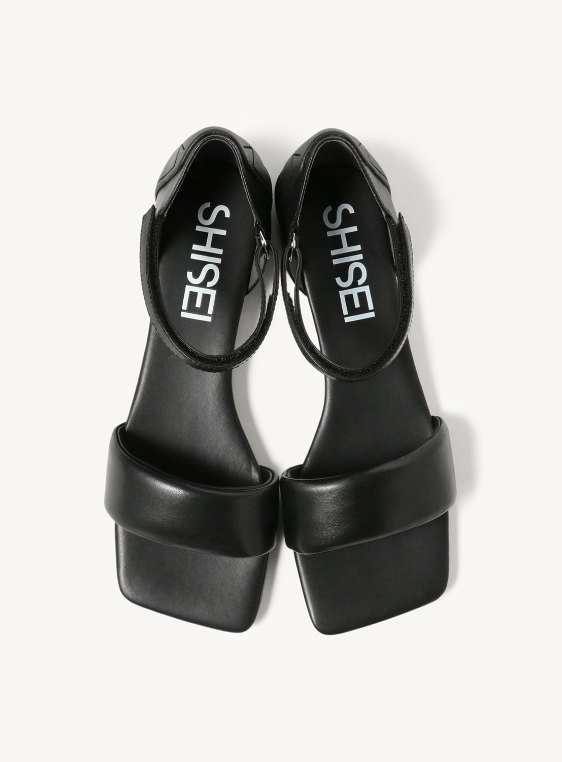 Black flat sandals, viewed from above, with wide toe straps and ankle straps.
