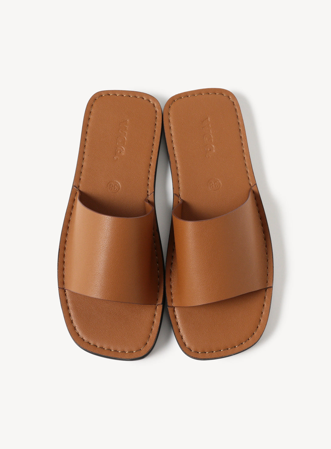 Top down view of brown leather sandal with stitching across the sole. 