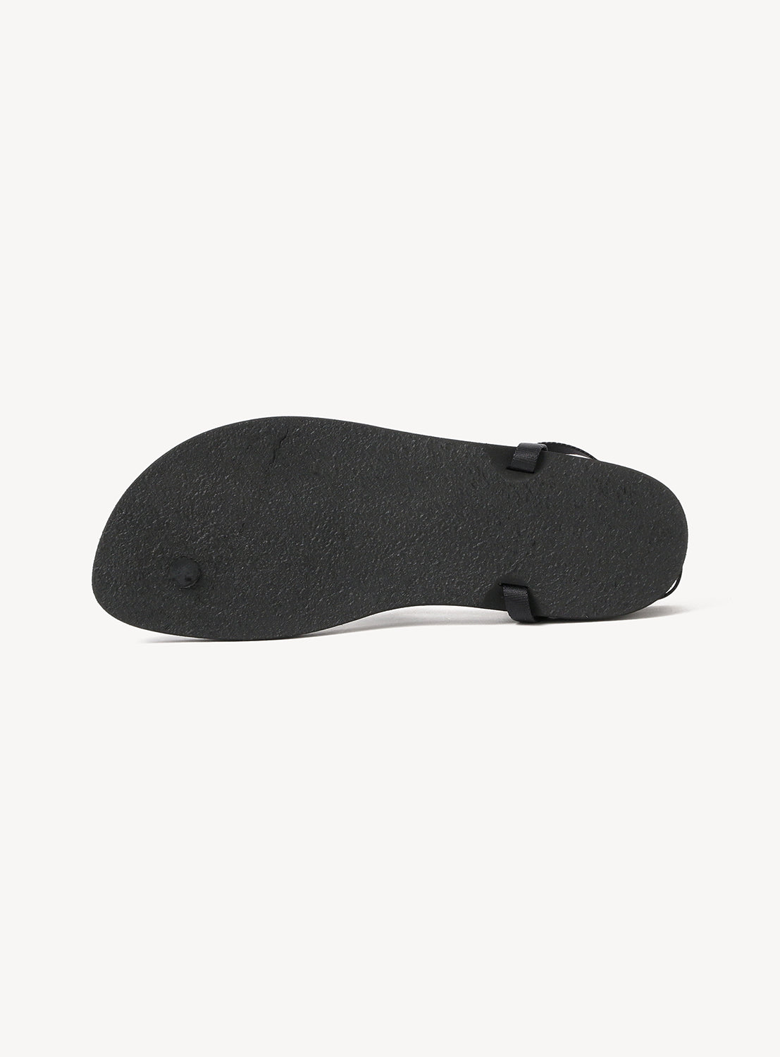 The image displays the bottom view of the BEAUTIFUL SHOES Minimalist Huarache Barefoot Sandals in black, showcasing their flat, textured sole and a glimpse of the side strap. The sandals present a minimalist aesthetic and are photographed against a white background.