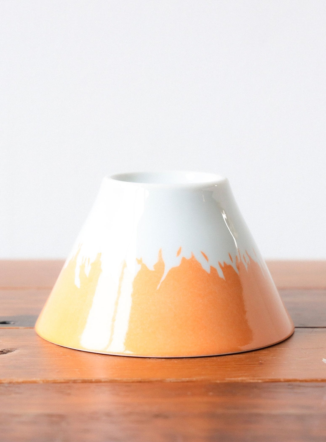 White and orange ceramic bowl on a wooden surface with a white background