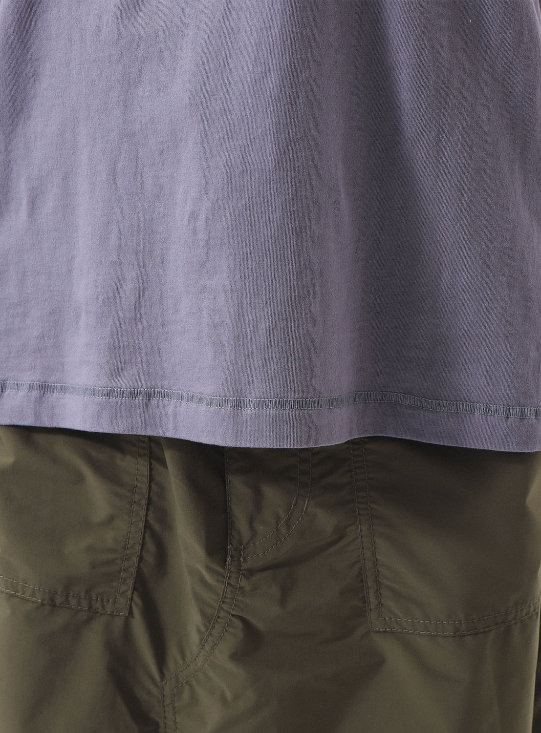 A close-up of a person wearing the BEAMS BOY Two-Tone Vintage Raglan T-shirt, untucked, paired with olive green pants, highlights the shirt’s worn-in look inspired by classic vintage raglan styling.