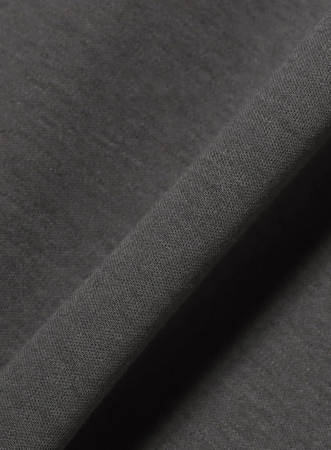 A close-up of the Silky Relaxed Fit Crew Neck T-Shirt by BEAMS showcases its dark gray, refined fabric with a soft, smooth texture. Folded diagonally, the material displays a subtle sheen and fine weave detail—ideal for this relaxed fit staple.