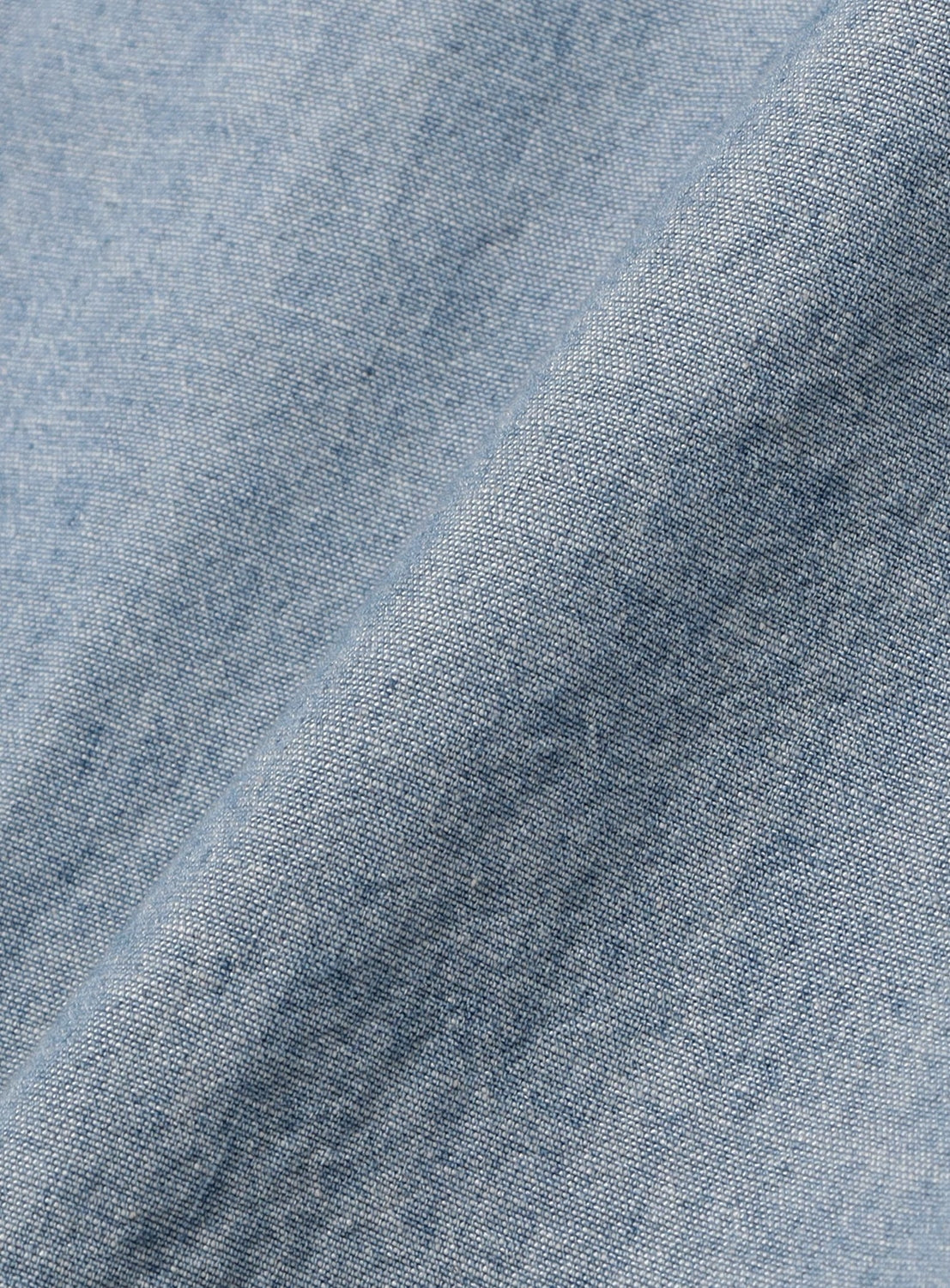 Close-up of light blue chambray fabric with a visible weave and soft folds, highlighting the texture and color variations—ideal for the relaxed fit of the BEAMS BOY Chambray Short-Sleeve Work Shirt.