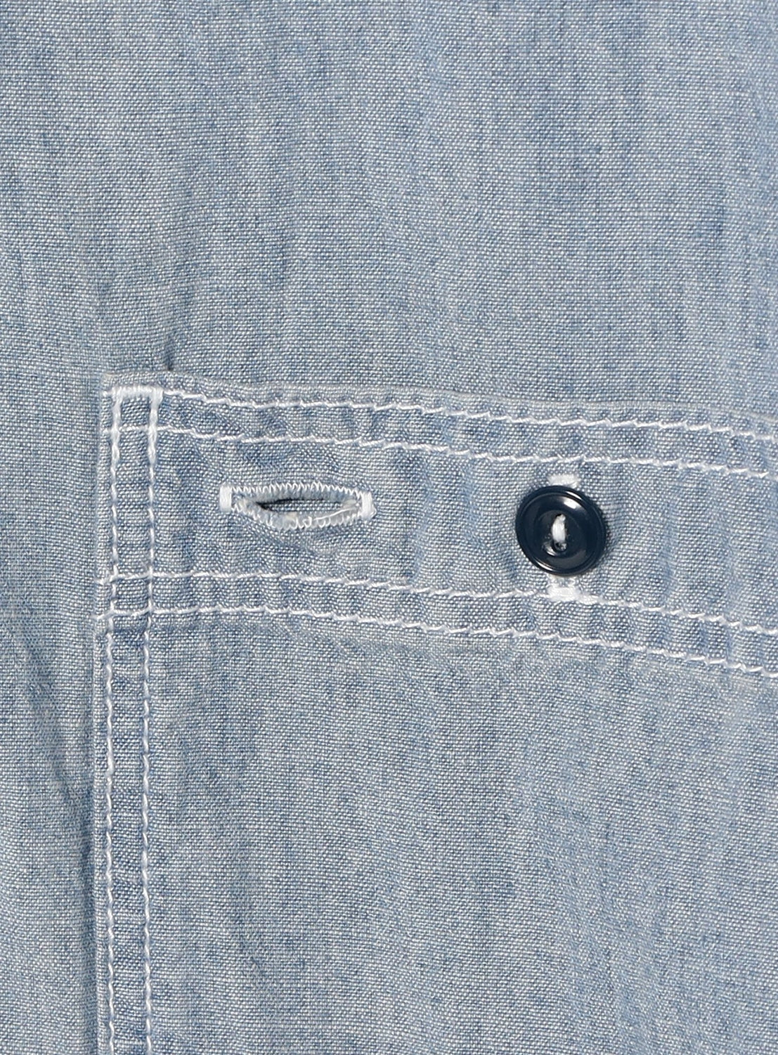 Close-up of the BEAMS BOY Chambray Short-Sleeve Work Shirt pocket in light blue, showing white stitching, a black button, and a buttonhole for a relaxed fit.