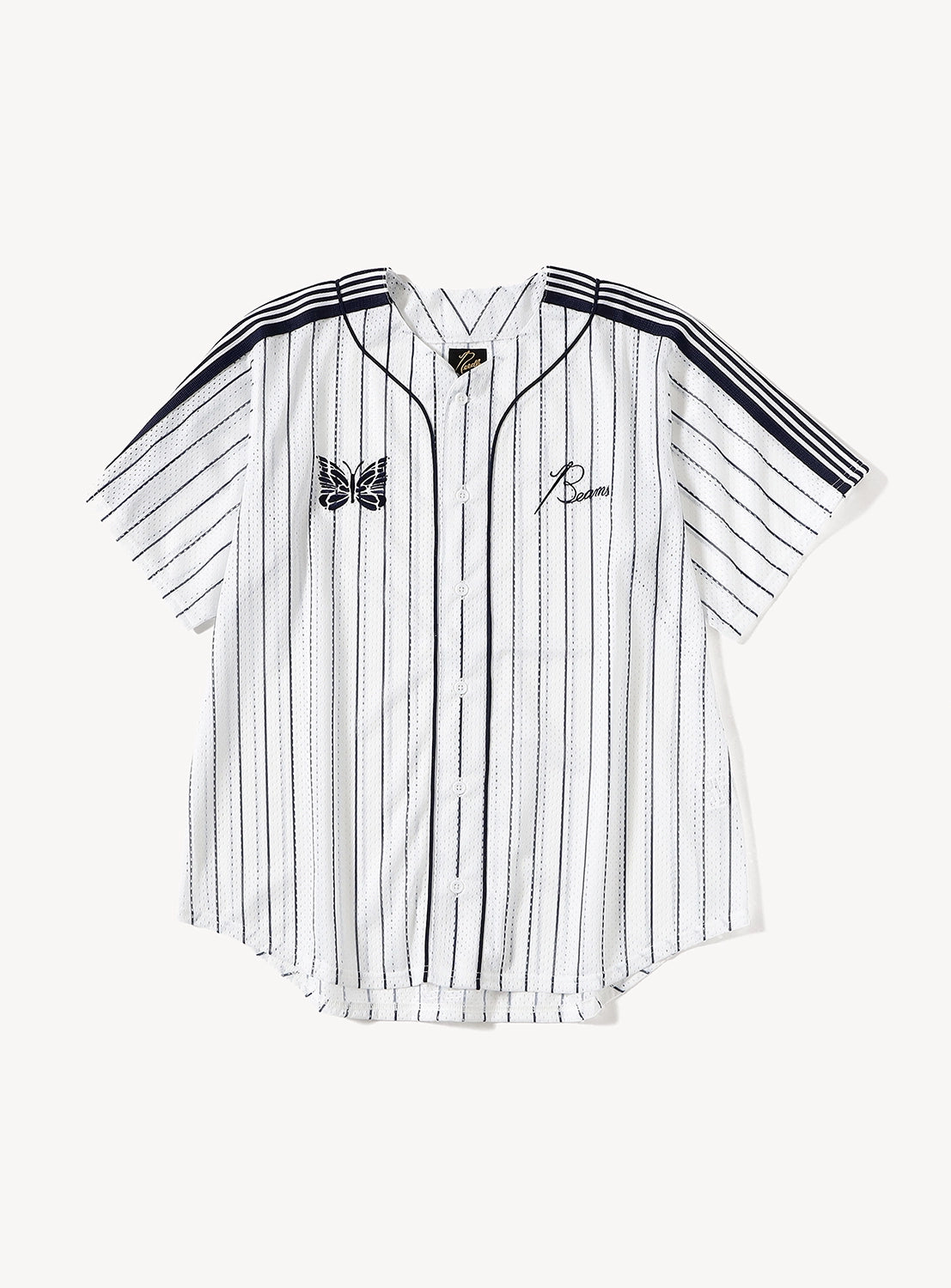 The [Exclusive] Needles 50th Baseball Shirt by NEEDLES is a white, short-sleeve, button-up baseball jersey featuring thin black vertical stripes, black piping, a butterfly patch on the left chest, and an “R” on the right chest. Channeling streetwear vibes reminiscent of BEAMS x Needles collaborations, this shirt is displayed laid flat against a white background.