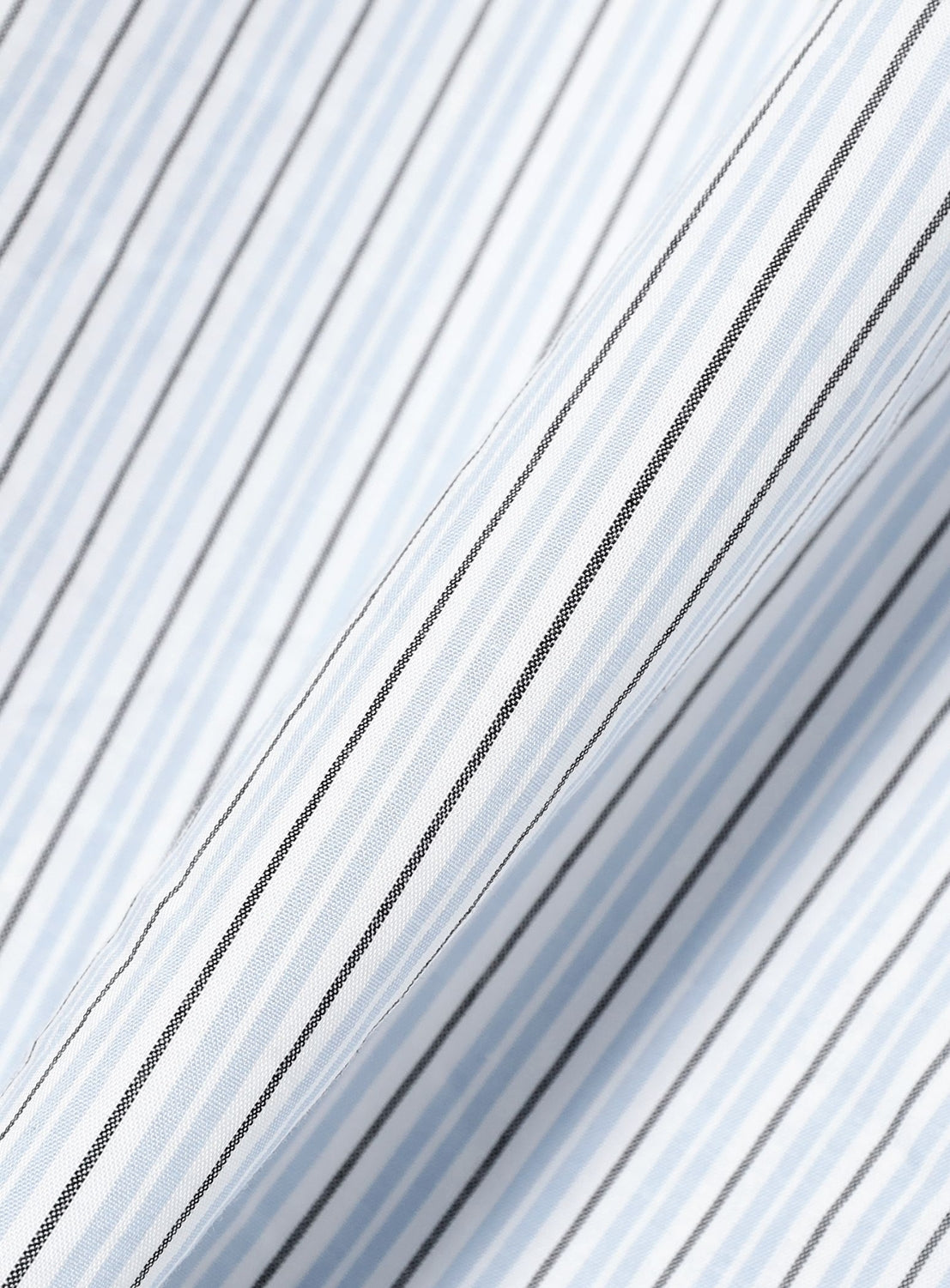 Close-up of white fabric with light blue and black vertical pinstripes, folded diagonally. The evenly repeating pattern creates a crisp, clean look, perfectly suited for the BEAMS Relaxed Fit Striped Shirt.