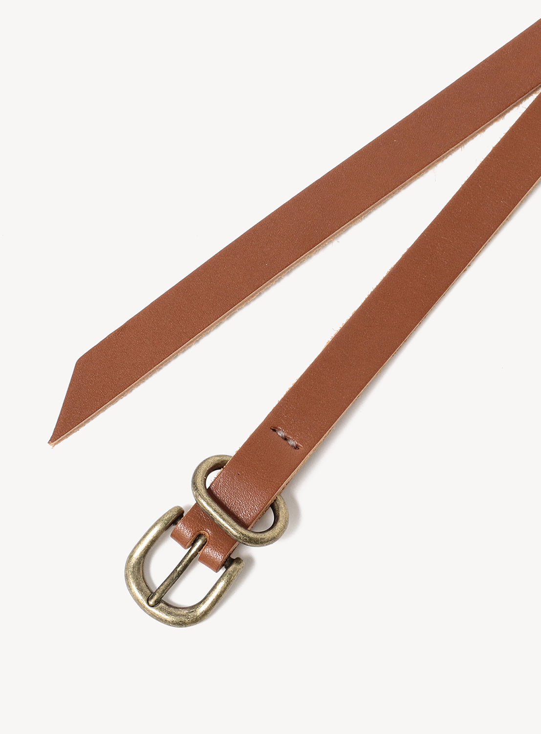 The Hender Scheme Extended Belt, crafted from vegetable-tanned cow leather with an antique brass oval buckle and pointed end, is shown on a white background.
