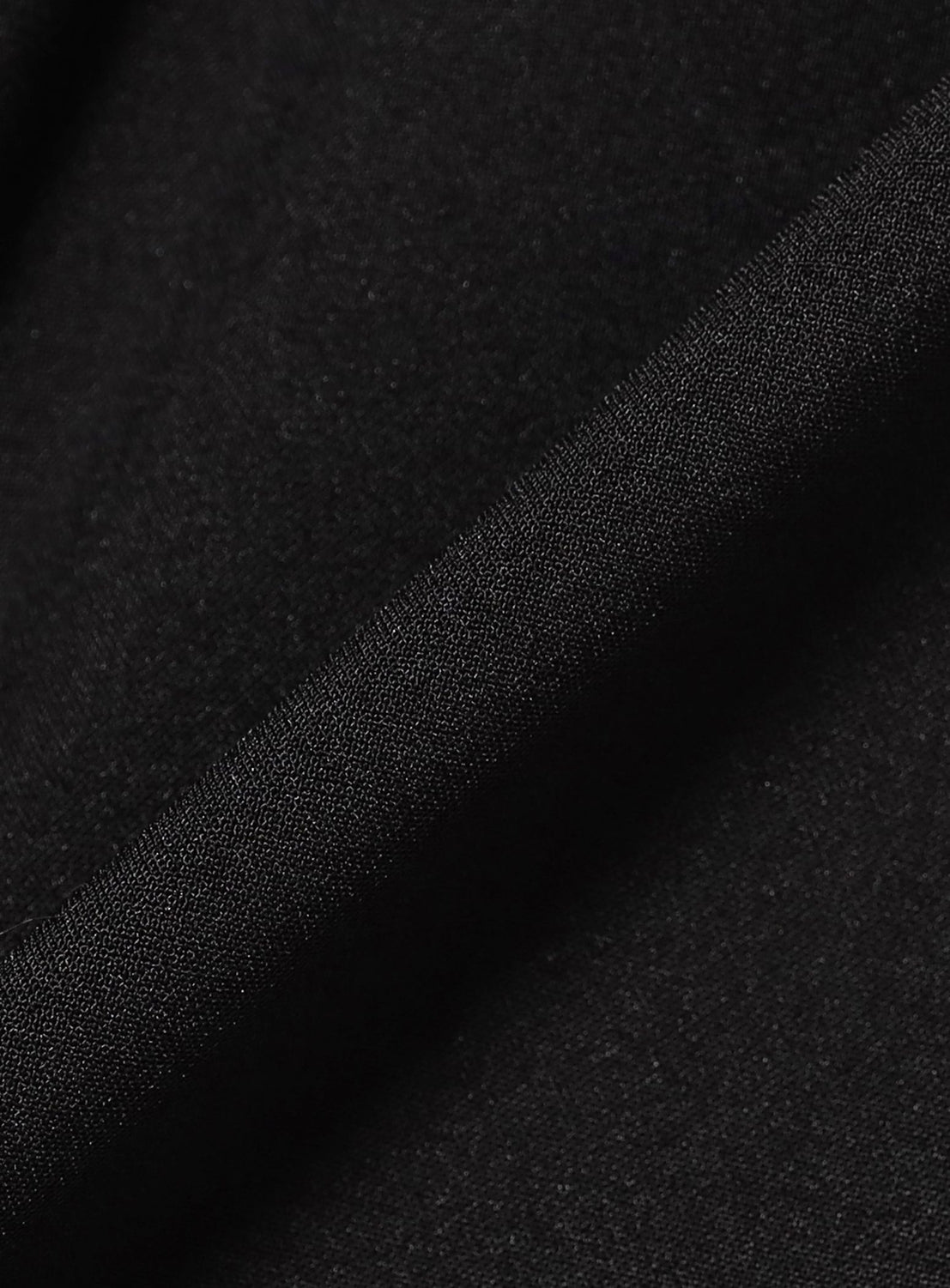 Close-up of black moisture-wicking polyester with a smooth, finely woven texture from BEAMS' Quick-Dry 2-Pleat Wide Tapered Easy Pants—ideal for relaxed fit and subtle light variations on the folded edge.