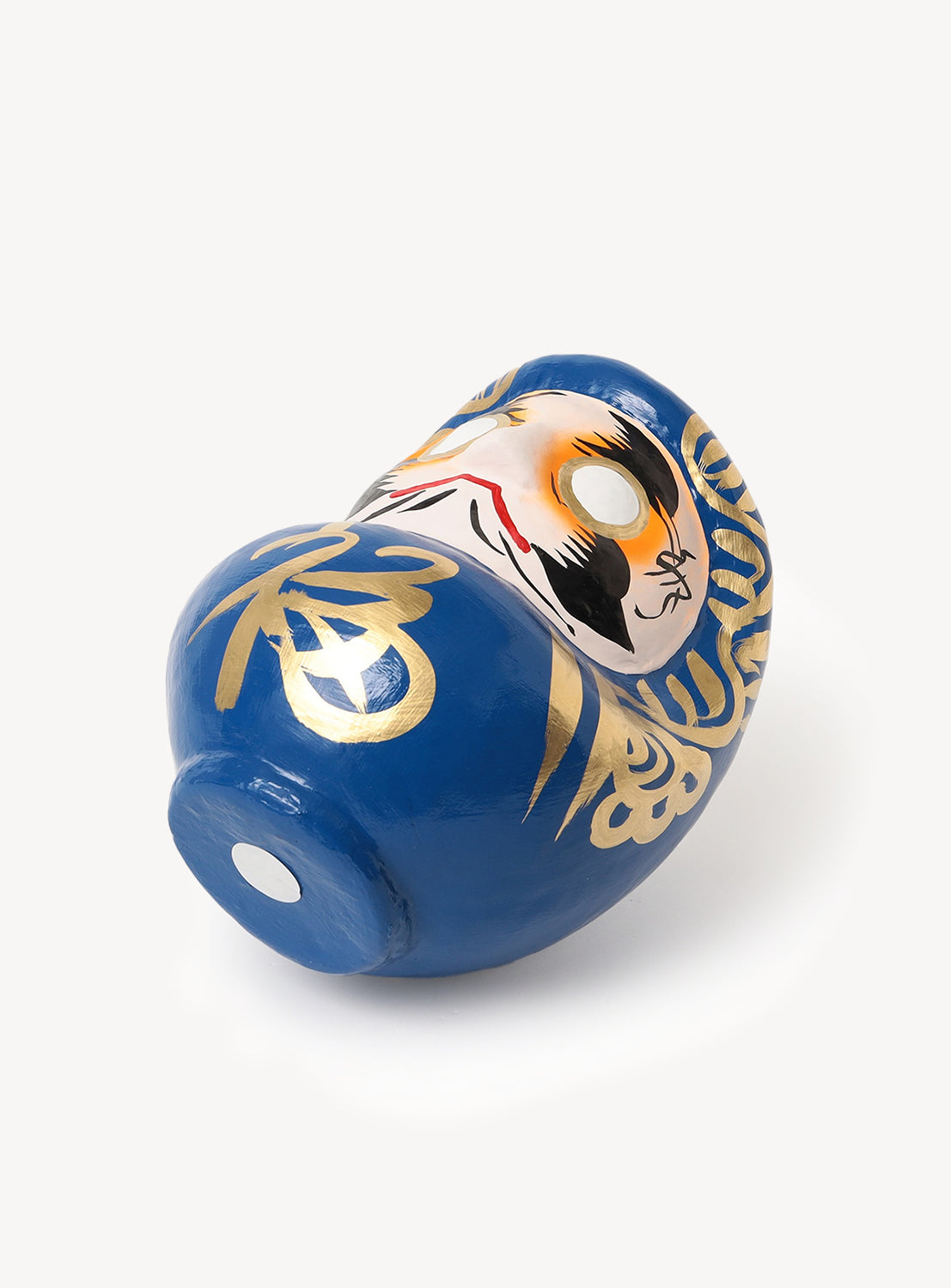A blue [Exclusive] BEAMS JAPAN Small Shirakawa Daruma LA with gold accents and a detailed painted face rests on its side against a white background, highlighting the exquisite Japanese craftsmanship of BEAMS JAPAN.