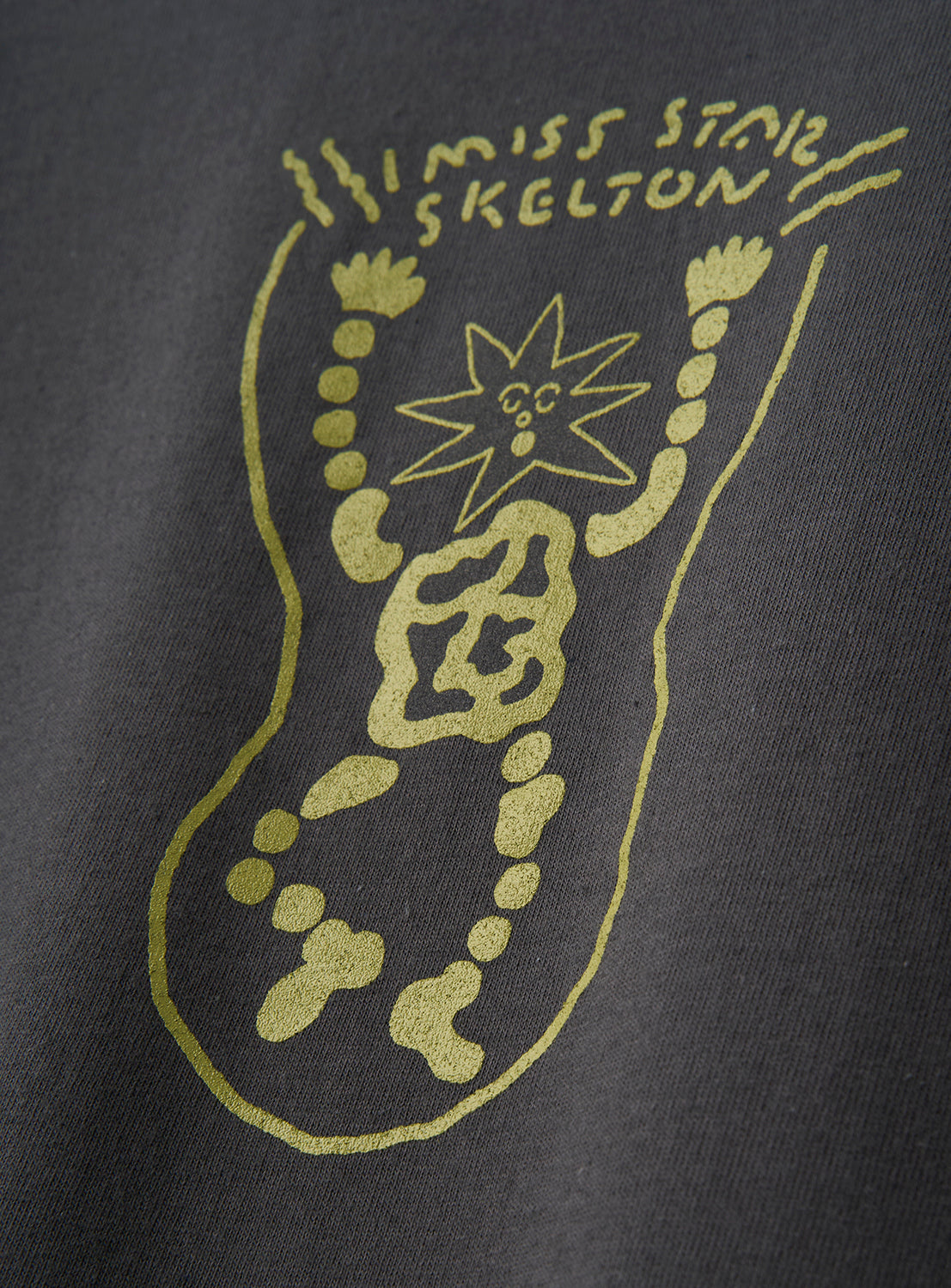 The norahi Starskel Hologram T-Shirt by norahi features a unique, hand-drawn yellow abstract skeleton with "I MISS STAR SKELTON" handwritten above it, printed on a dark fabric background. This graphic tee offers a relaxed fit and modern style.