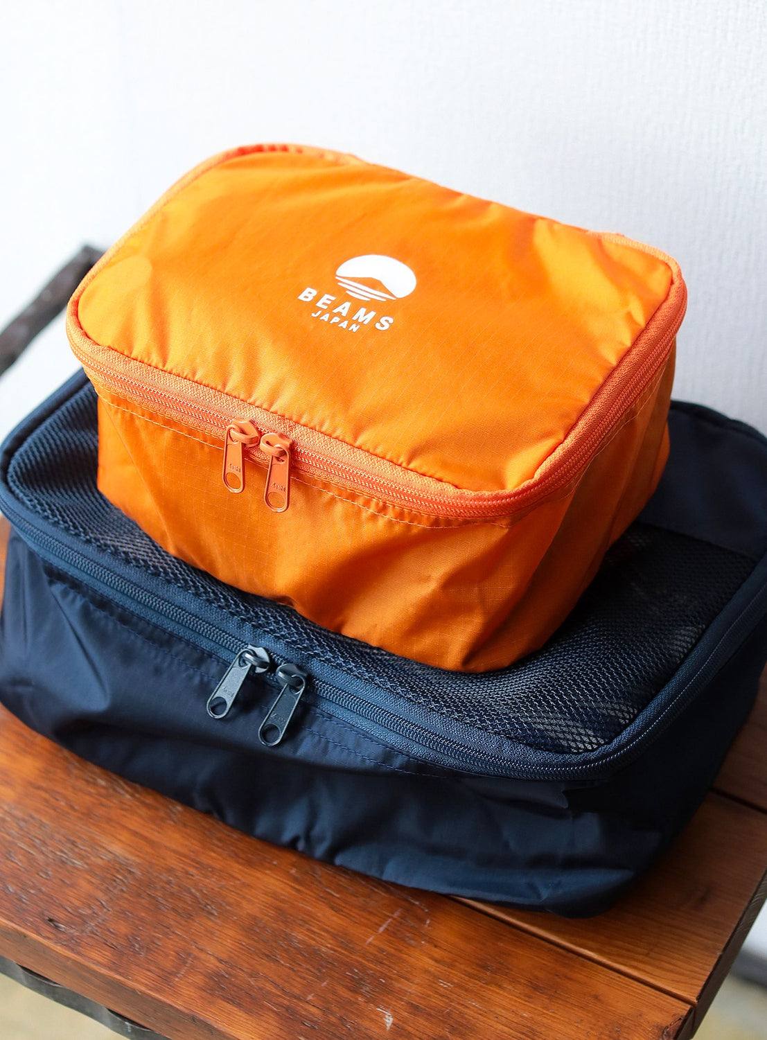 Orange and blue packing cubes with a visible brand logo on a wooden surface.