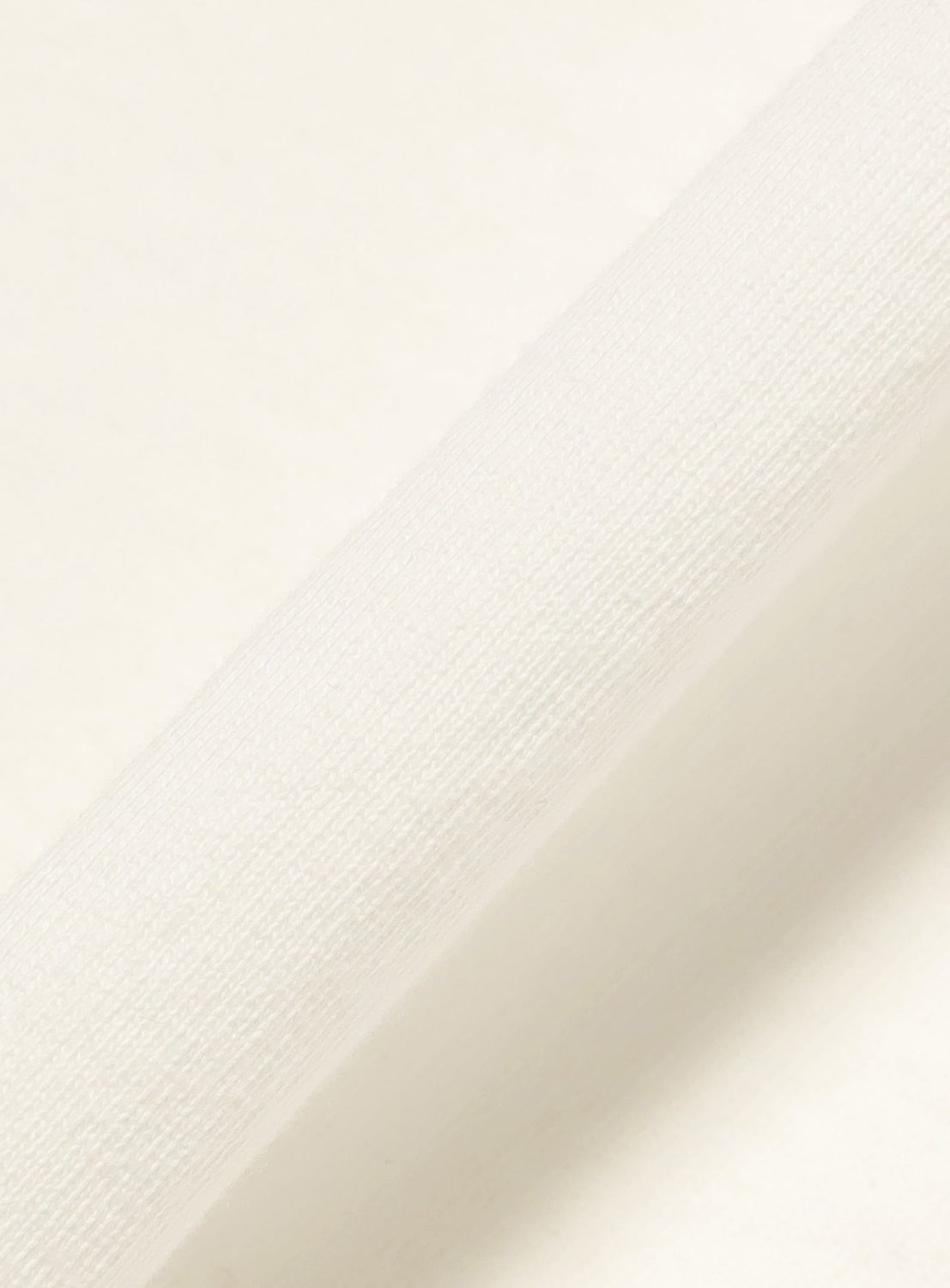 A close-up of the Symbol Logo Tee by F-LAGSTUF-F showcases its white textured fabric set diagonally against a plain background—perfect for creating a vintage-inspired look with its soft pigment-dye finish.