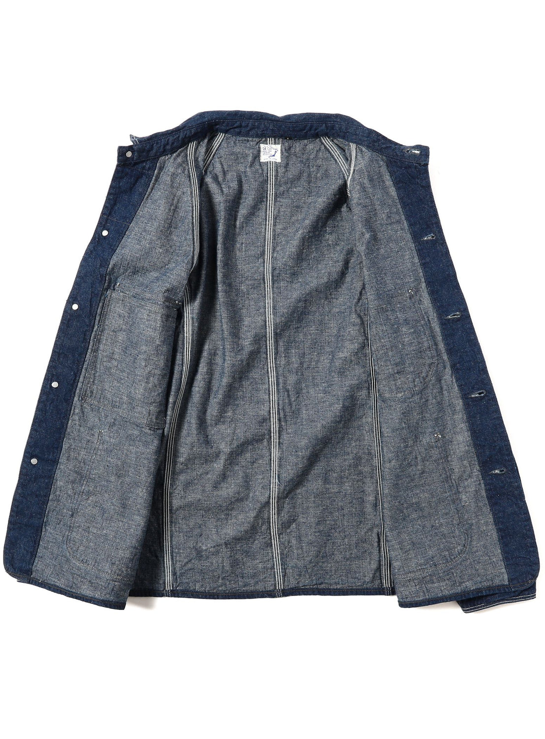 The orSlow 1950 Denim Coverall Jacket, crafted in Japan from lightweight blue denim, is displayed laid flat and opened to reveal its gray inner lining with visible seams and button closures along the edges.
