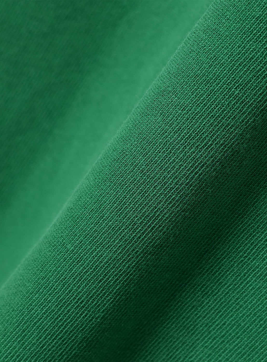 Close-up of green heavyweight knit fabric with a diagonal fold, highlighting the smooth weave and vintage look of the [Exclusive] BEAMS x Champion Heavyweight Pigment-Dyed Rugby Shirt by CHAMPION.