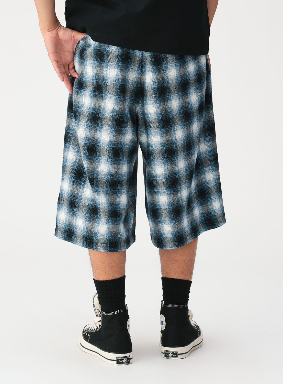 A person wearing BEAMS Check Shorts in a blue and white ombre pattern, paired with black high-top sneakers.