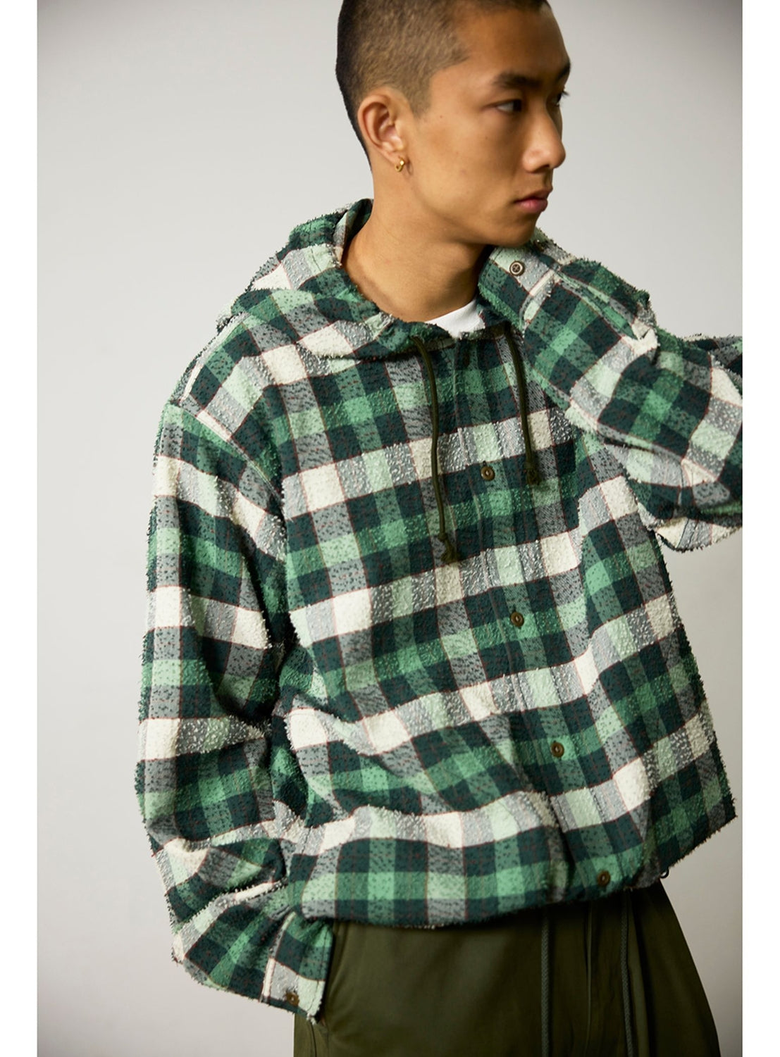 A person wearing a BEAMS Bouclé Flannel Hooded Shirt in a vintage-inspired green and white check pattern with textured fabric and frayed edges.