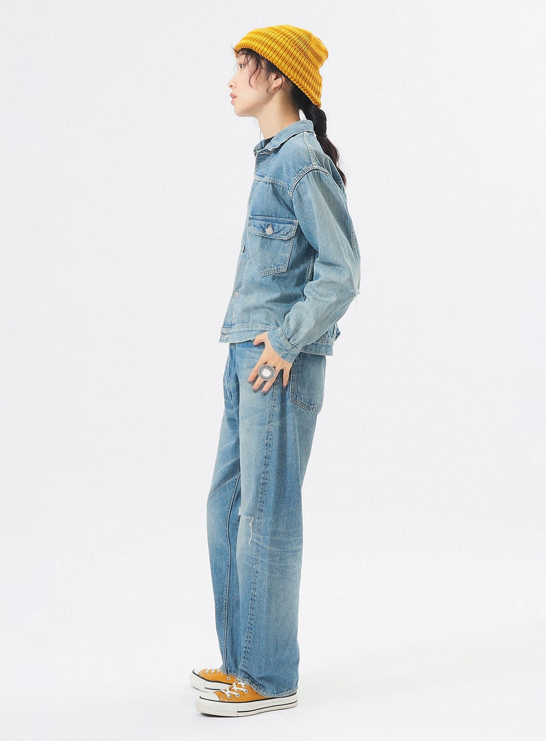 Person wearing a yellow beanie, denim jacket, and jeans on a white background