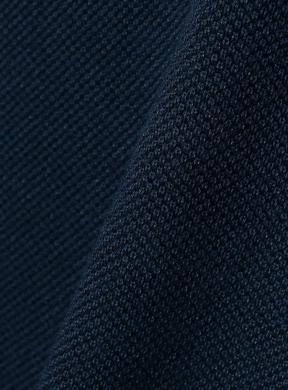 Close-up of the dark navy Moss Stitch Skipper Polo Shirt by crepuscule, showing a fine moss stitch weave and visible diagonal seam, typical of this relaxed fit design.