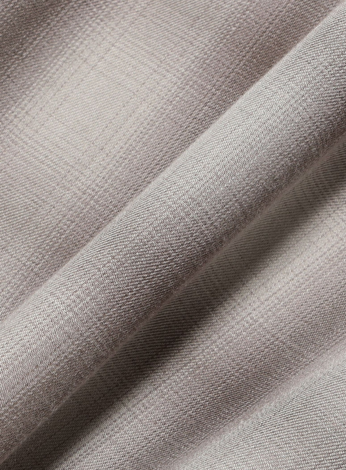 Close-up of a light gray, finely woven fabric with a subtle check pattern on a diagonal fold of the BEAMS Layered Check Shirt.