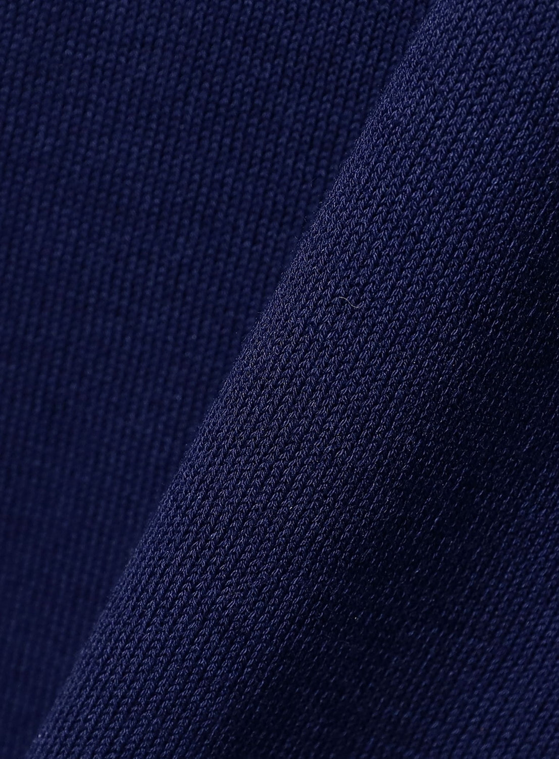 Close-up of crepuscule’s Short Sleeve Polo in dark blue, featuring ribbed knit fabric with a relaxed fit. The material is slightly folded, showing a visible seam and subtle shadows along the crease.