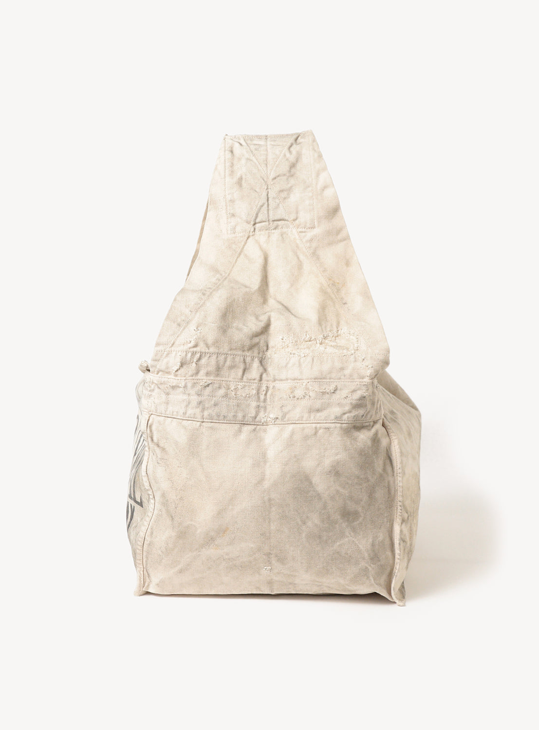 Side view of a white canvas tote bag, highlighting the strap and the bag's profile.
