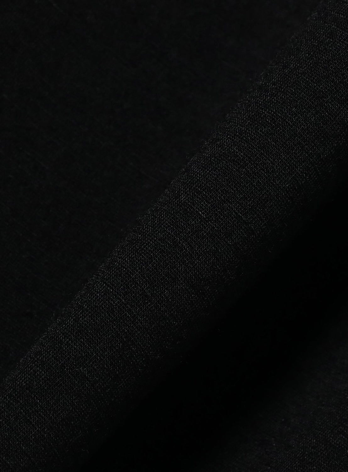 A close-up of black merino wool fabric from BEAMS’ the A - Washable Merino Wool T-Shirt, showing its subtle weave and folded edge—ideal for a relaxed look or half-sleeve tee.